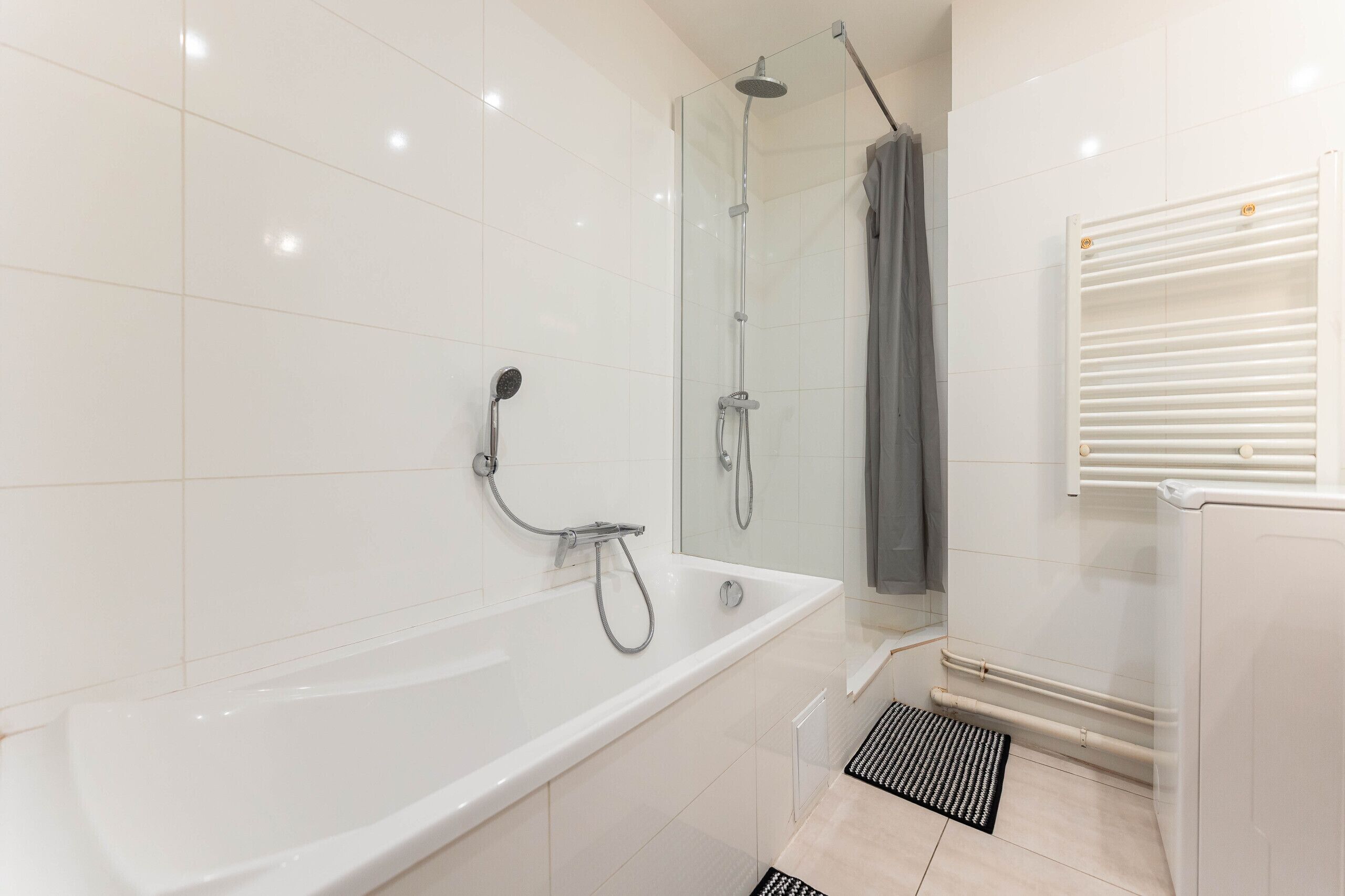 A modern bathroom with a bathtub, shower, and a glass-enclosed shower area.
