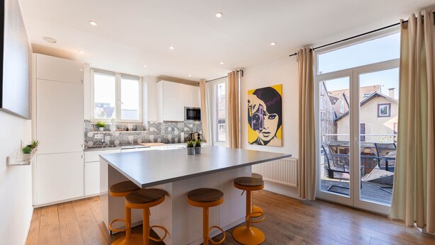 Une cuisine moderne dotée d’un îlot central, de tabourets de bar et d’une grande fenêtre.