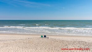 Een strand met twee stoelen gericht op de oceaan.