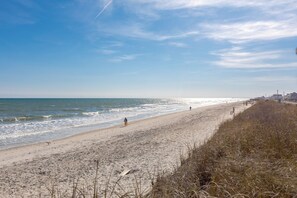 Une plage avec une promenade en bois qui longe le rivage et mène à l’eau.