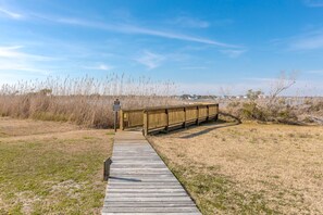 Une promenade en bois mène à une structure également en bois, sur laquelle est apposé un panneau d’avertissement.