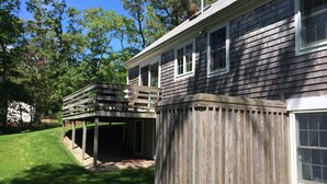 A two-story house with a covered patio and a wooden deck. - Updated Vacation Home Close to Town and Beaches (2221) (Orleans)