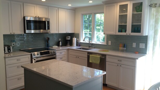 A modern kitchen with white cabinets, a stainless steel range, a microwave, and a large island with a marble countertop. - Updated Vacation Home Close to Town and Beaches (2221) (Orleans)