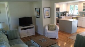 A living room with a TV, sofa, and coffee table. There's a kitchen area with a microwave and cabinets. - Updated Vacation Home Close to Town and Beaches (2221) (Orleans)