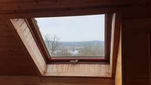 Ein Oberlicht in einem Holzraum mit Blick auf eine Landschaft und Wasser.