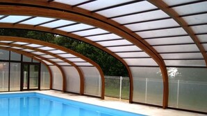 Ein Hallenbad mit hölzernem Bogenbau und Glaswänden.