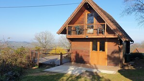 Eine Holzhütte mit Balkon, einer Holzterrasse und Blick auf die Landschaft.