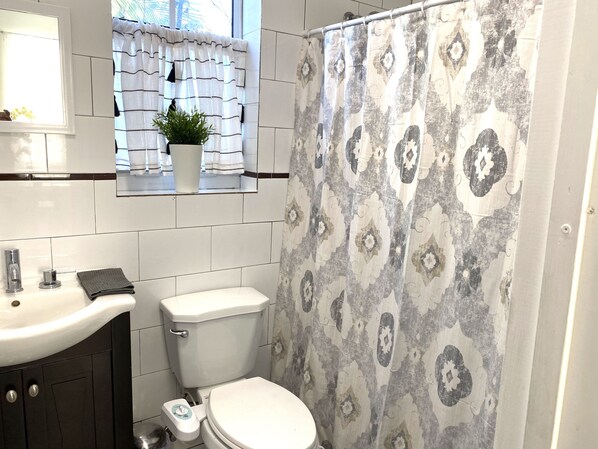 A bathroom with a toilet, sink, and a shower curtain with a geometric pattern. - Amazing Property Comfortable for Larger groups (Miami)