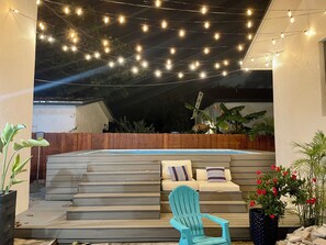 A patio area with steps leading to a seating area, string lights overhead, and a hot tub. - Amazing Property Comfortable for Larger groups (Miami)
