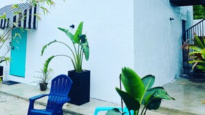 Un edificio bianco con una porta blu, una sedia blu e piante in vaso.