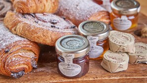 A variety of pastries and jars of preserves on a wooden surface. - The Fleet (Tewkesbury)
