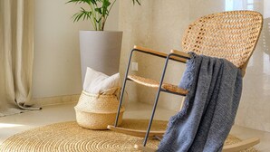 Une chaise en osier avec une structure en métal, un panier tressé et une plante en pot.
