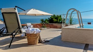 Un espace aménagé au bord de la piscine, avec une chaise, un parasol et un panier en osier contenant des serviettes.