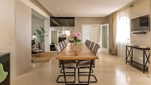 Un espace repas moderne avec une longue table, des chaises et un vase de fleurs.