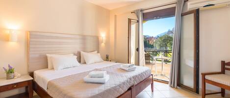 A hotel room with a large bed, a nightstand, a chair, and a balcony with a view.