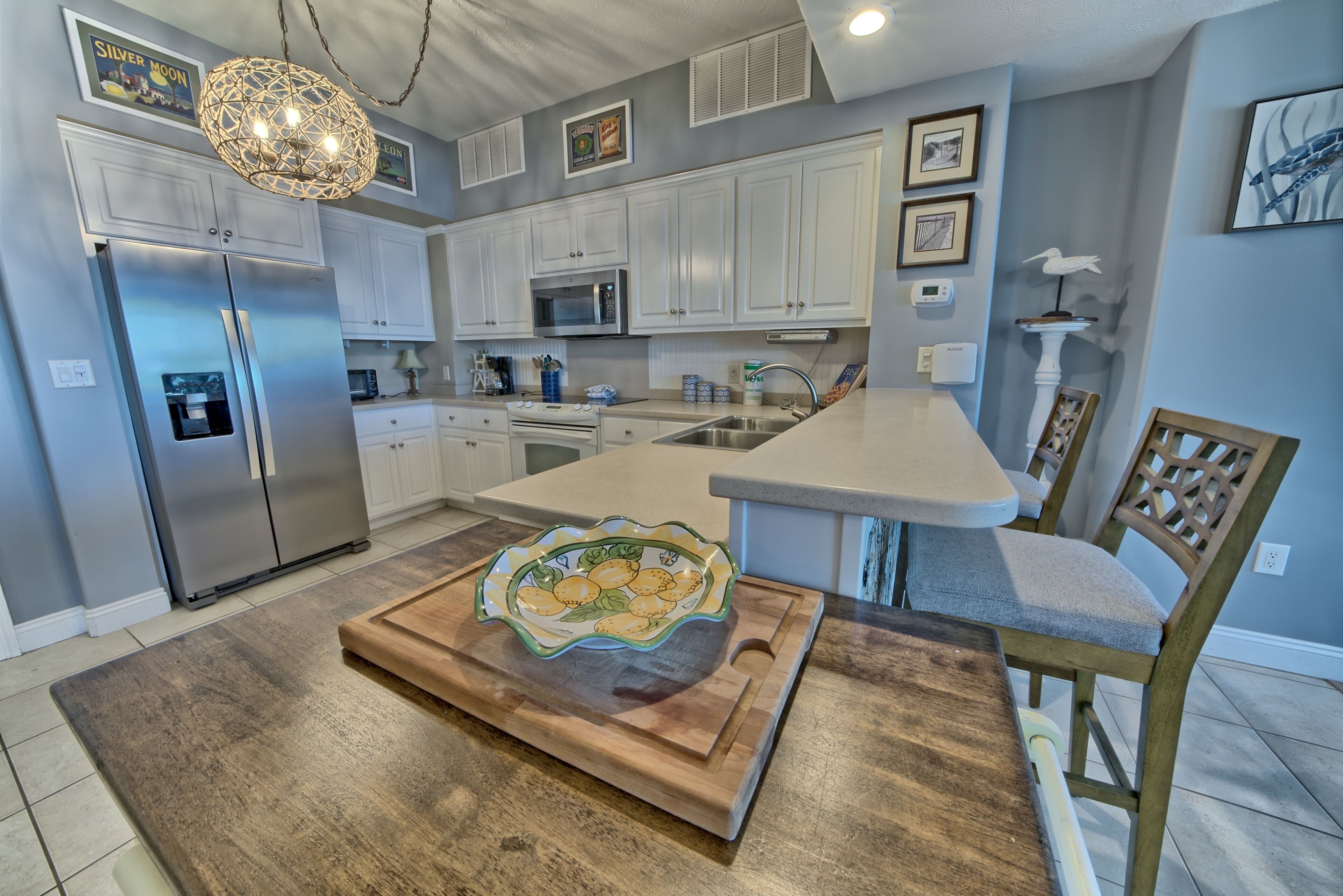 Una cocina moderna con armarios blancos, electrodomésticos de acero inoxidable y una isla central con un cuenco decorativo.