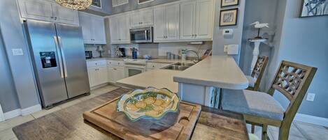 Una cocina moderna con armarios blancos, electrodomésticos de acero inoxidable y una isla central con un cuenco decorativo.