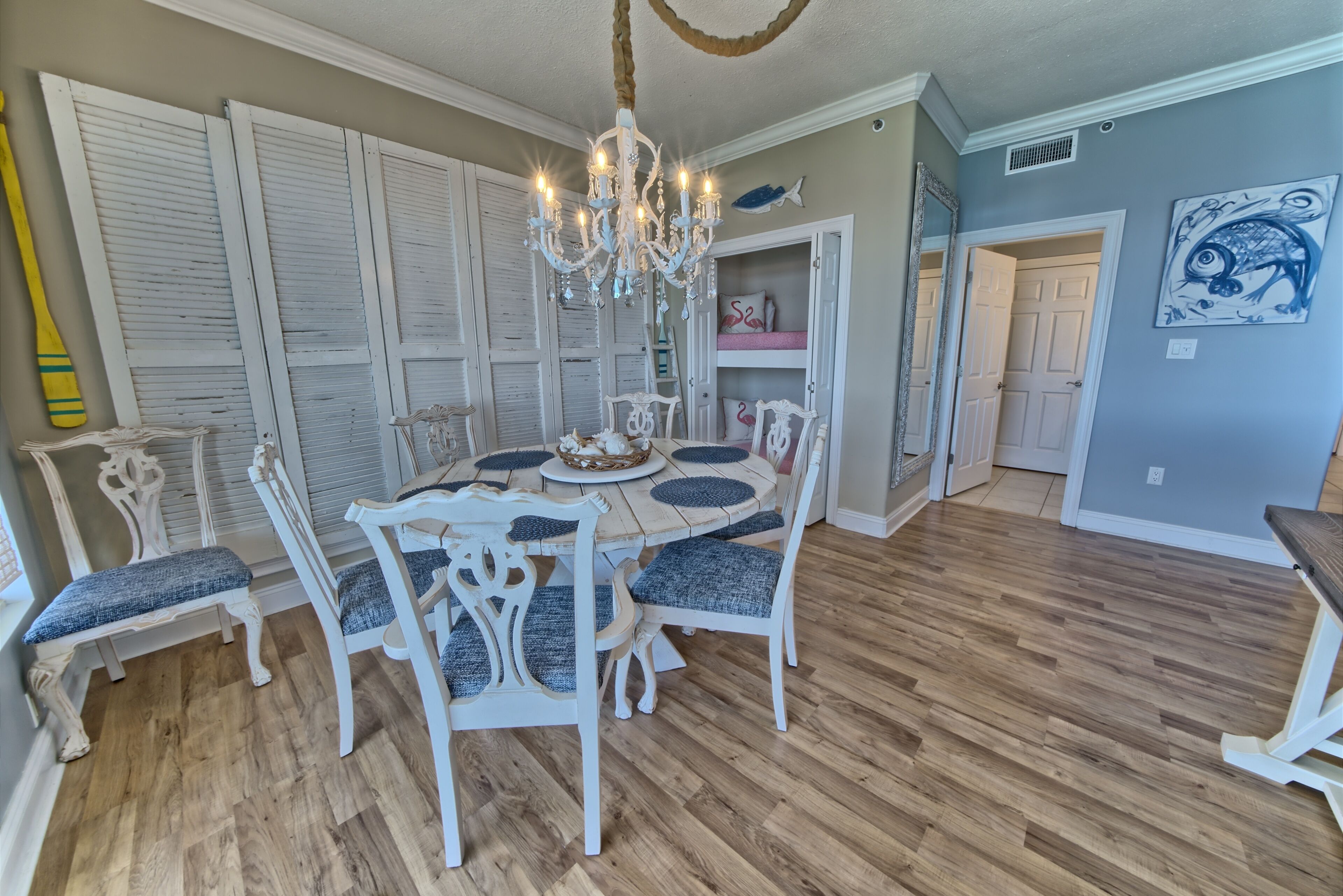 A dining area with a round table, white chairs, and a chandelier.
