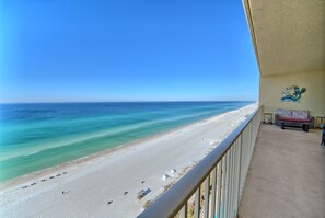 A beach view from a balcony with a clear sky, a sandy beach, and a small building. - Cozy Oceanfront Condo with Beachside Pool - Unit 1602 by RedAwning (Panama City Beach)
