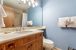 Een badkamer met een houten wastafelmeubel, een wastafel, een spiegel en een toilet.