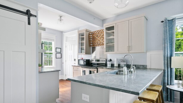 A modern kitchen with a large island, white cabinetry, and a view of the outdoors. - The Blackberry Suite | 3 BR 2BA | 2nd Floor Condo (Charleston)