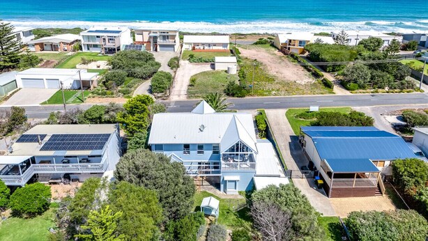 Vista aérea de una zona residencial costera con casas, una carretera y una playa.