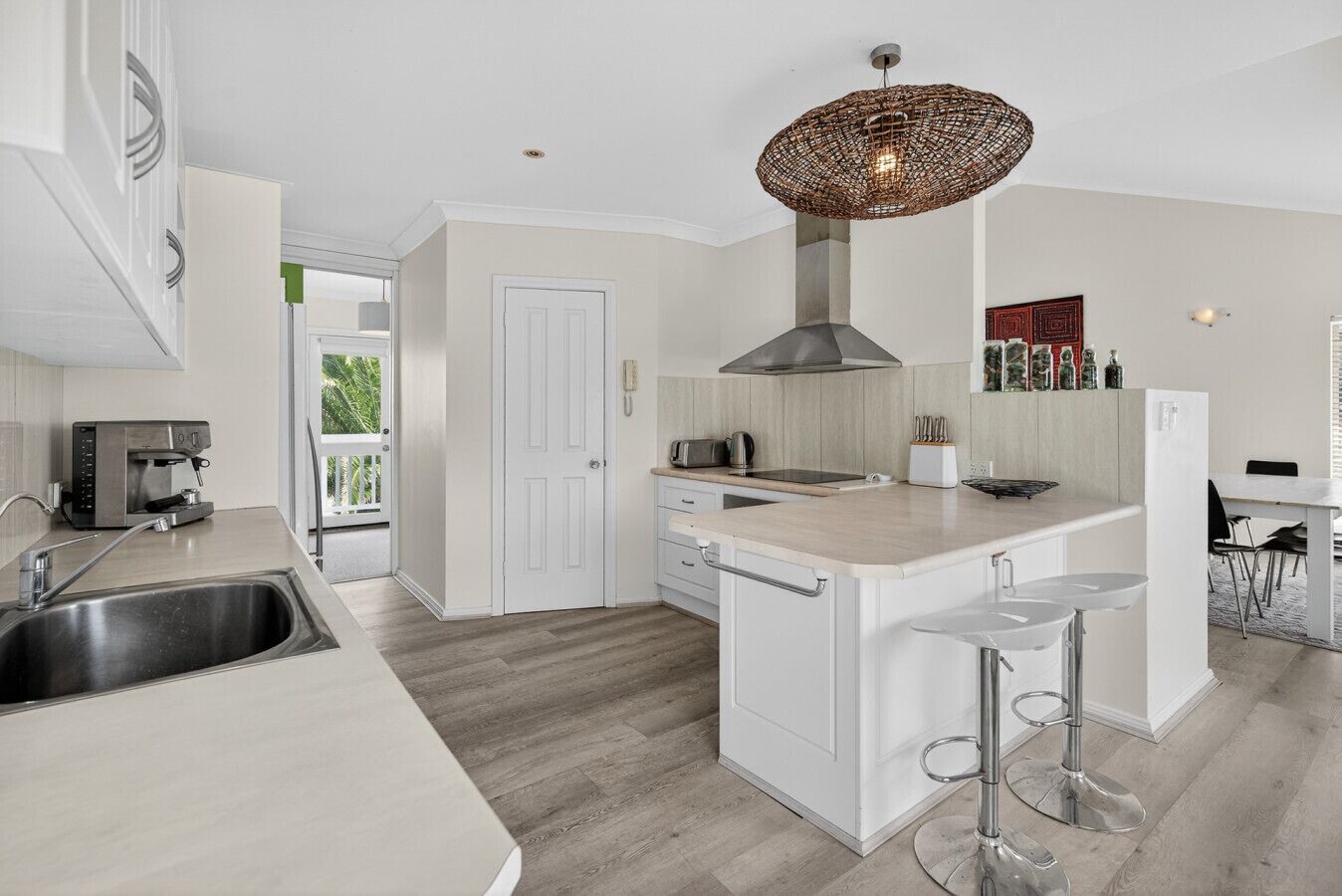 A modern kitchen with a central island, a built-in oven, a coffee machine, and a hanging light fixture.