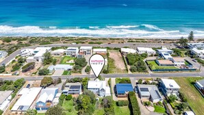 Vista aérea de una zona residencial costera con casas modernas, una vista despejada del océano y un letrero que indica 'southcoast realty'.