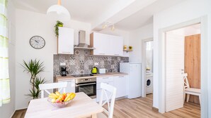 A modern kitchen with white cabinets, a patterned backsplash, and a dining area with a table and chairs. - Away from everyone, close to everything (Dubrovnik)