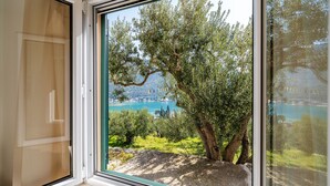 A window with a view of a tree and a body of water. - Away from everyone, close to everything (Dubrovnik)