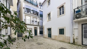 A cobblestone courtyard with buildings on either side, featuring balconies and doors. - 3 guest apartment in the center of Alfama (Lisboa)