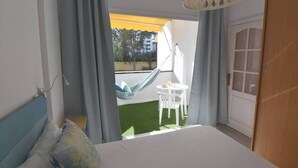 A bedroom with a bed, a small table, and a hammock. - Agaete Park 128 By Pride Holiday Rentals (Playa del Ingles)