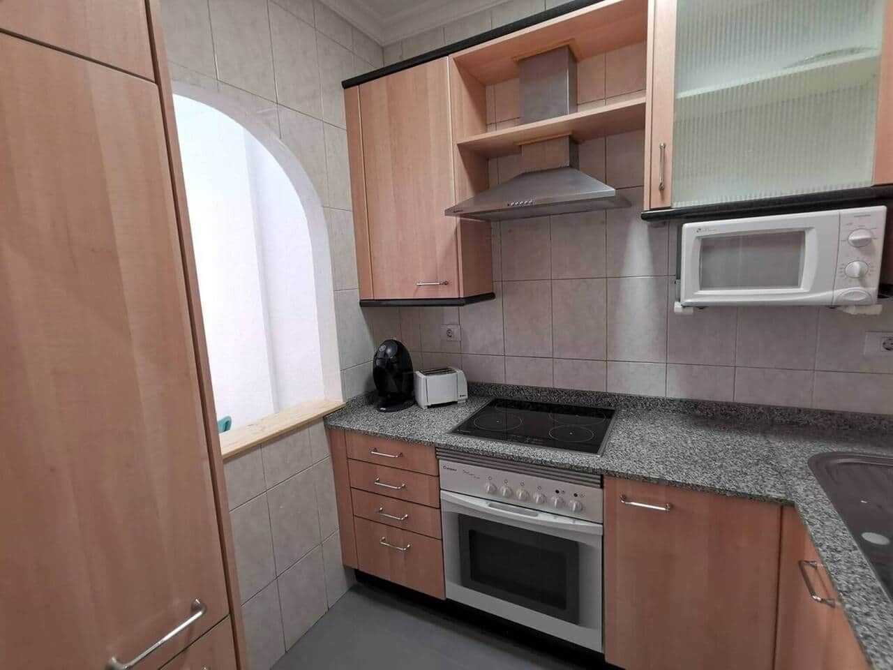 Una cocina compacta con estufa, microondas y tostadora sobre la encimera.