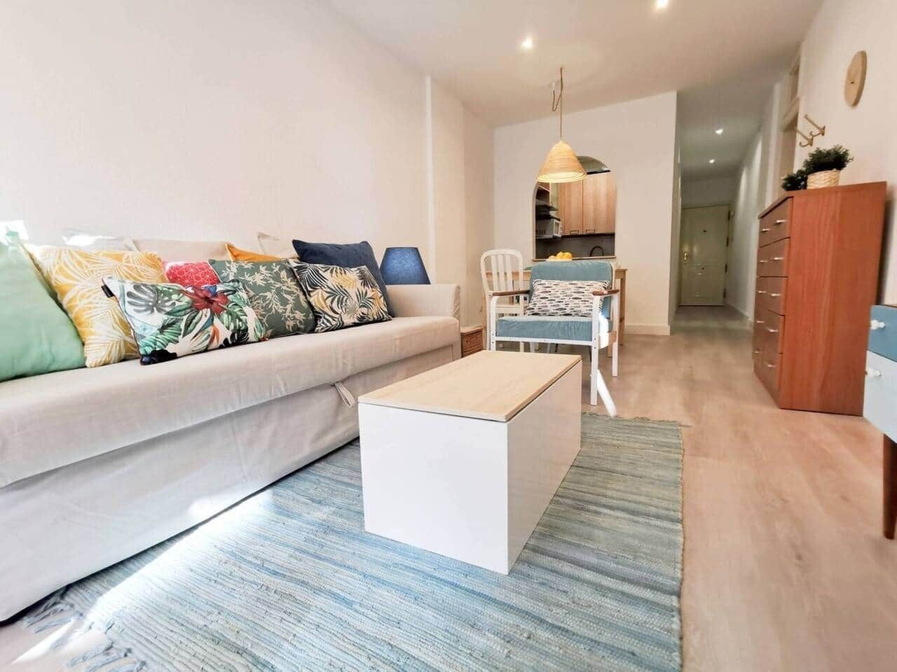 A modern living room with a sofa, coffee table, and dining area.