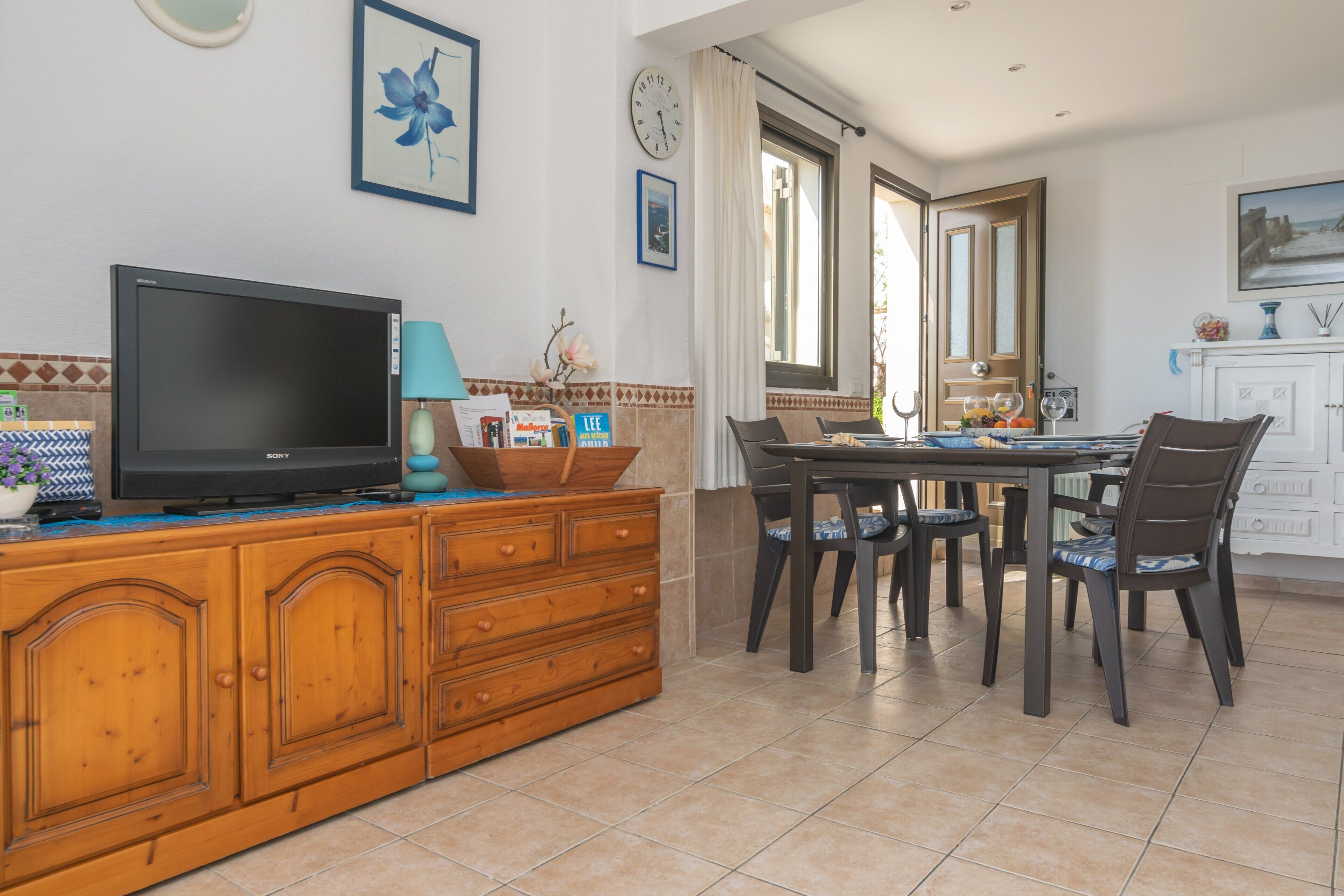 Un área de comedor con un mueble de madera, un televisor y una mesa de comedor con sillas.