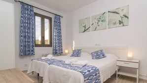 Une chambre double avec deux lits, une table en bois et une table de chevet avec une lampe.