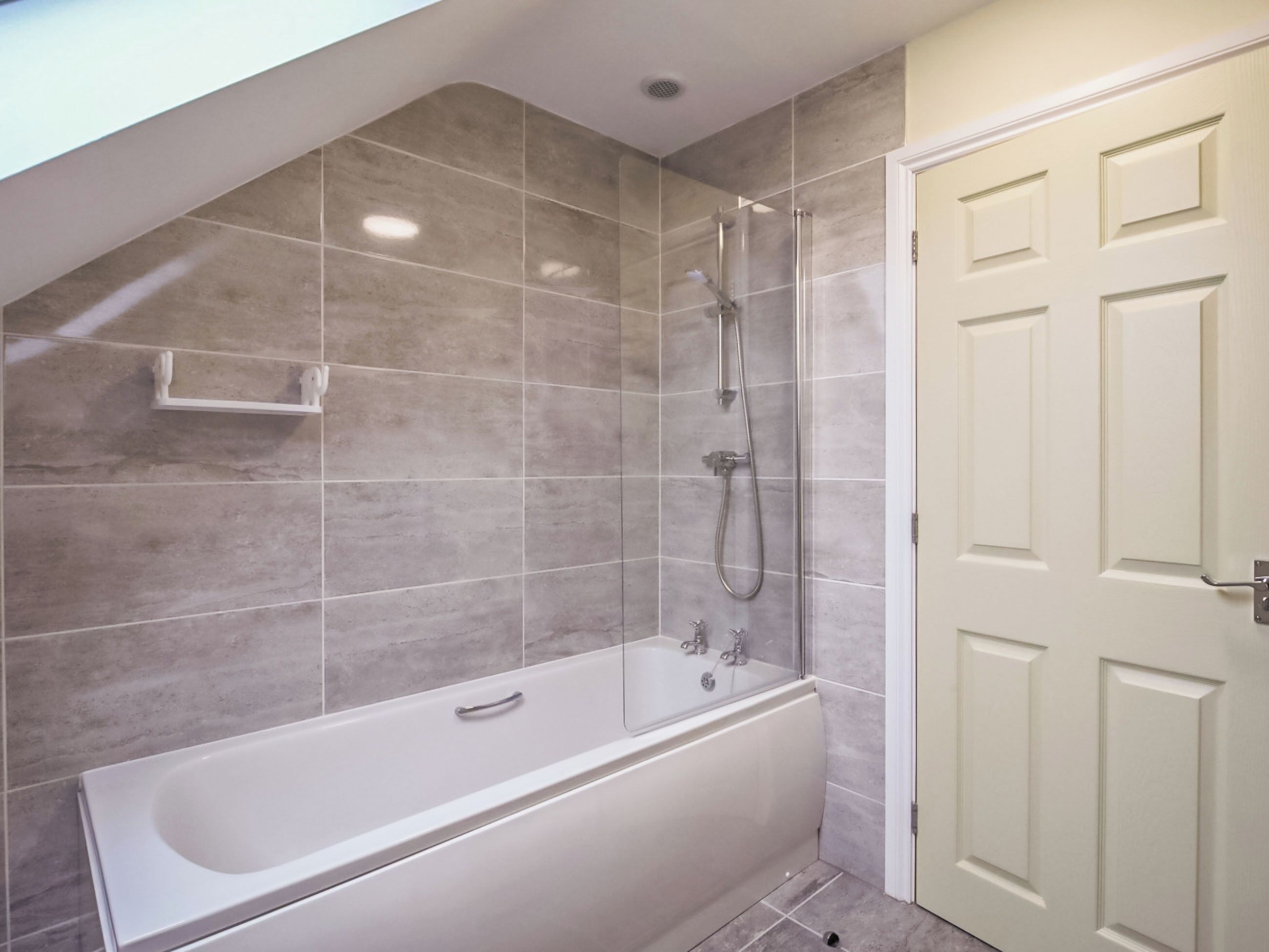 A modern bathroom with a bathtub, shower, and a door.