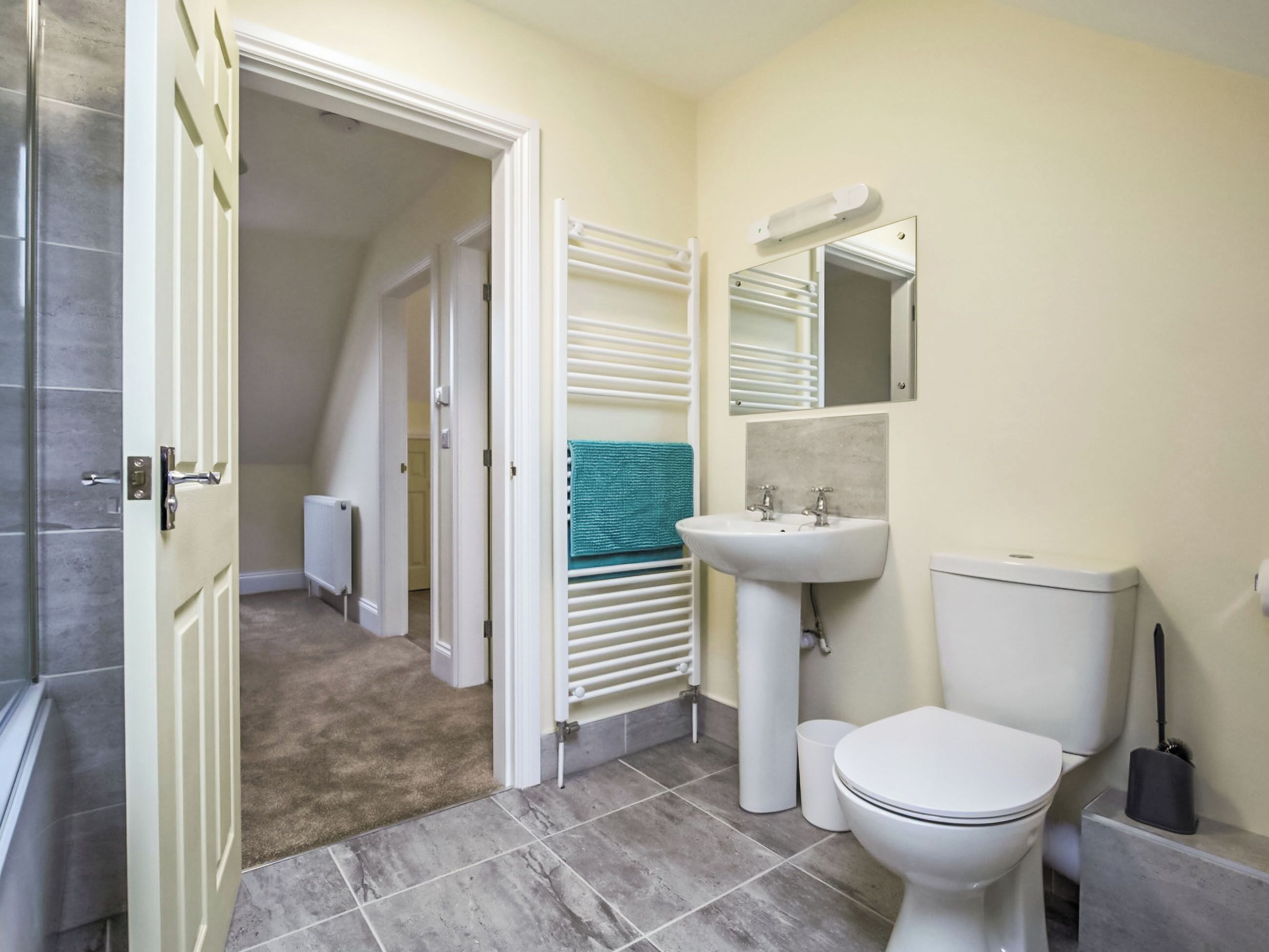 A bathroom with a toilet, sink, towel rack, and a mirror.