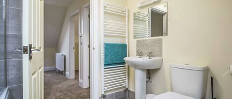 A bathroom with a toilet, sink, towel rack, and a mirror.