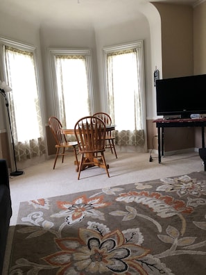Relax in this spacious living room with a large window, dining table, and flat-screen TV.
