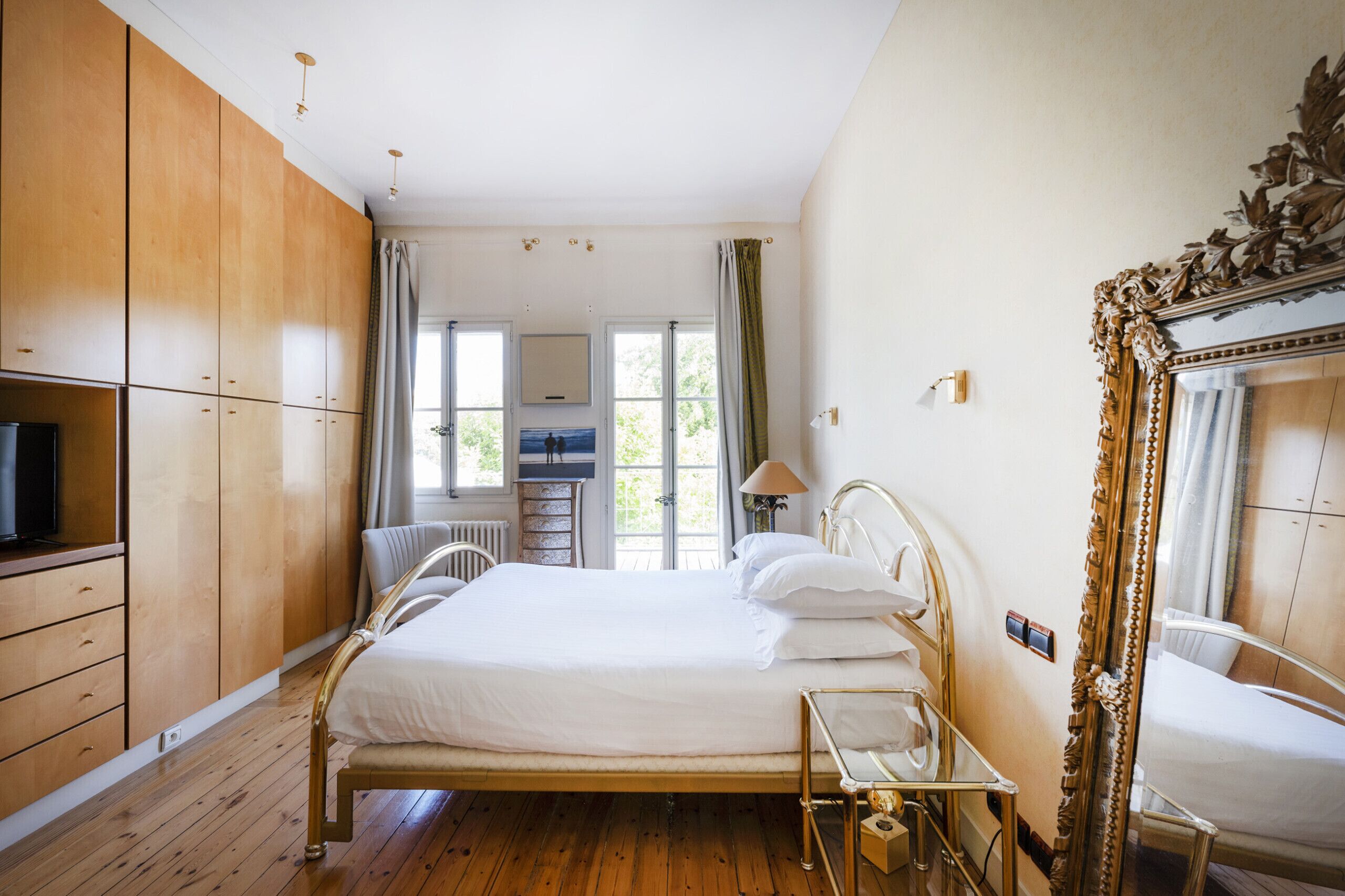 A bedroom with a wooden bed, a large mirror, and a television.