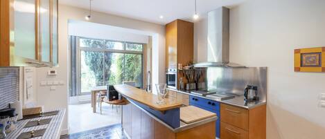 A modern kitchen with a central island, stainless steel appliances, and a large window providing natural light.