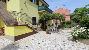 A yellow building with a tiled patio, a staircase, and potted plants. - Apartment Stojana (Rovinj)