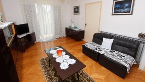 Una sala de estar con un sofá, una mesa de centro, un televisor y una puerta.