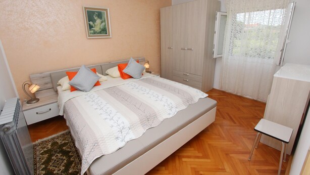 A bedroom with a bed, nightstands, a wardrobe, and a window with curtains. - Apartment Stojana (Rovinj)