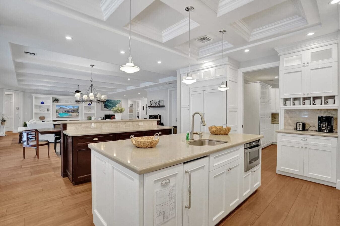 A spacious kitchen with white cabinetry, a large island with a sink, and pendant lighting.