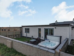 Ein modernes Haus mit Whirlpool, kleiner Terrasse und einer Steinmauer.