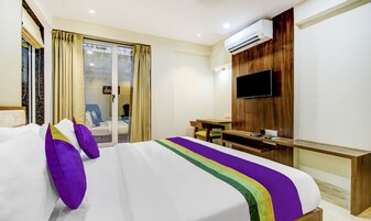 Una habitación de hotel con cama, escritorio, silla, aire acondicionado y televisor.