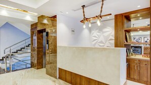 Ein modernes Interieur mit einer Marmortreppe, einem hölzernen Empfangstresen und einem geometrischen Wanddesign.