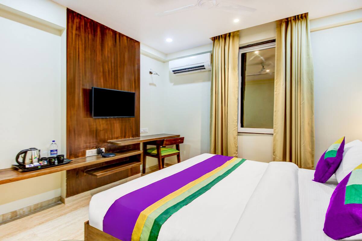 Ein Hotelzimmer mit einem Bett, einem Schreibtisch, einem Fernseher und einer Klimaanlage.